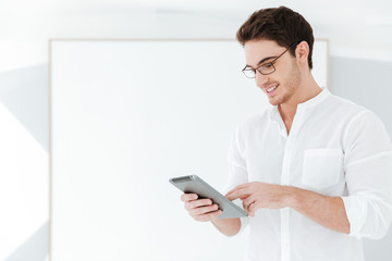 Happy man using tablet computer near big board.