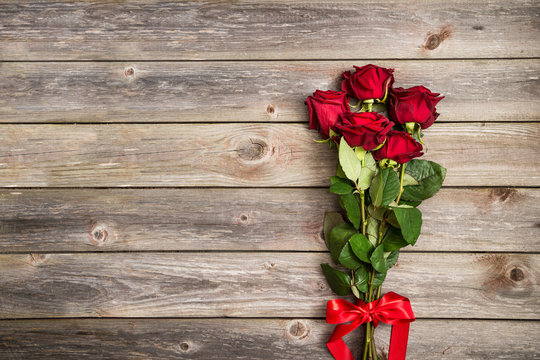 bouquet of red roses with bow on wood background. Valentines Day