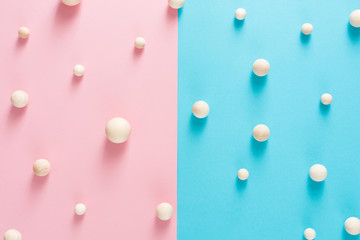 Wooden craft spheres make pattern on blue and pink paper in halves