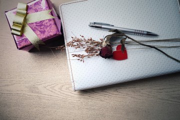 notebook, gift box and dry rose on wooden table. The memories of love concept.