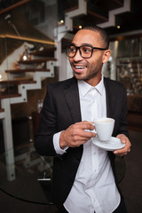 Vertical image of happy african man with coffee in hotel
