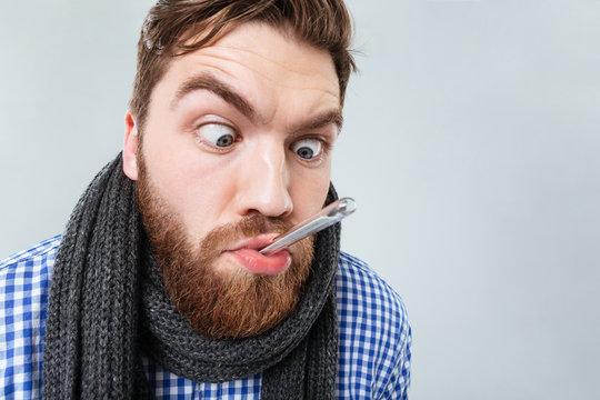 Funny bearded man in scarf with thermometer at his mouth