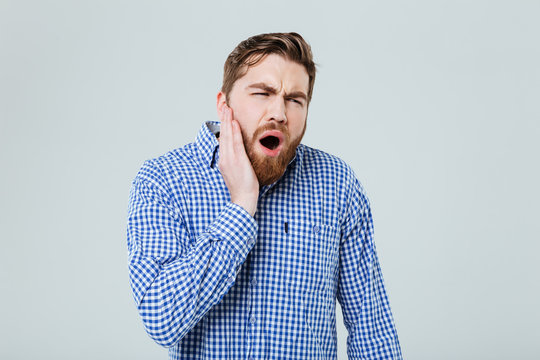Depressed bearded young man shouting and having toothache - Powered by Adobe