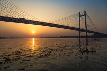 Fototapeta na wymiar Vidyasagar Setu the longest cable bridge in India at sunset. Photograph taken from a boat near Princep ghat, Kolkata.