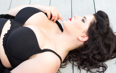 Young beautiful plus size model  lying on the wooden background,