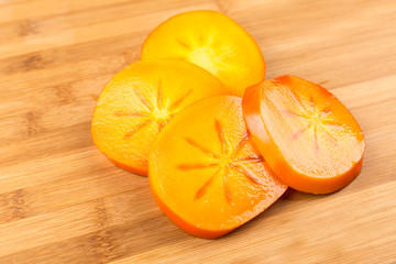 Sliced up persimmon isolated on a wood background