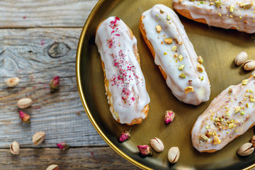 Vanilla eclairs with small roses and pistachios.