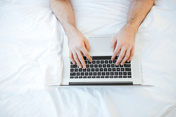 Fototapeta na wymiar Top view of man using laptop on bed