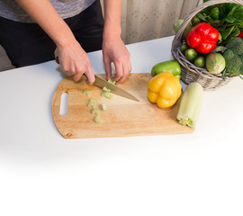 Man preparing a salad, searching for recipes on-line using a laptop hands close up, kitchen tools and food ingredients 