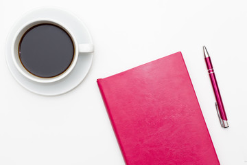 pink diary, pen and a Cup of black coffee on white. business minimal concept for women. Flat lay, top view.