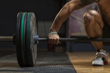 Sporty young man with naked torso lifting barbell