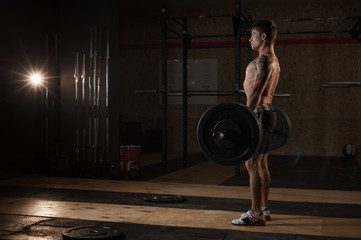 Obraz na płótnie Canvas Young muscular man lifting barbell in gym