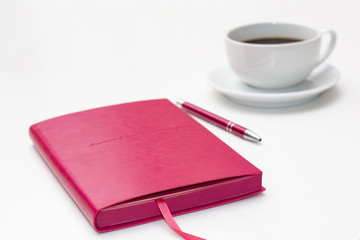 pink diary with pen and a Cup of black coffee on white. business minimal concept for women.