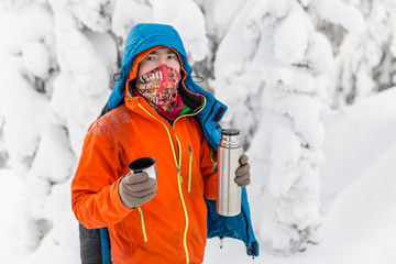 Fototapeta na wymiar Man pours hot tea out of thermos in winter forest