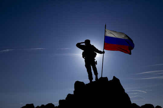 soldier on top of a mountain with a Russian flag