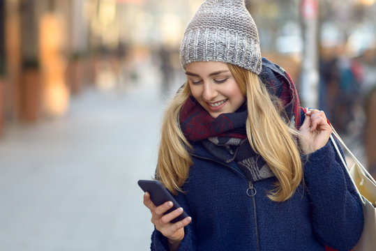 Modische junge Frau mit Einkaufstaschen und Handy 