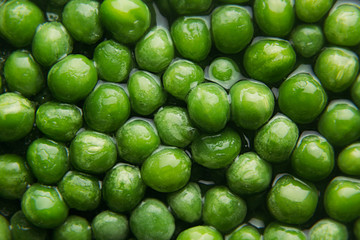 Wet fresh green peas in water closeup as background. Healthy vitamin food.