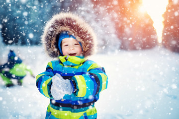 Boy in knitted hat, gloves and scarf outdoors at snowfall