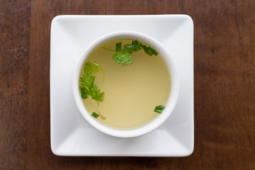 Clear soup with coriander in a white bowl, Top view.