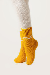 Female legs in white stockings and yellow knitted socks.