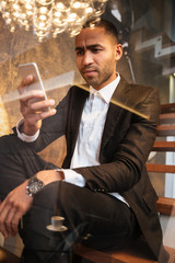 Vertical image of african man using phone on stairs