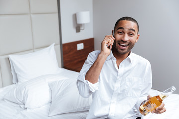 African man talking at phone on bed