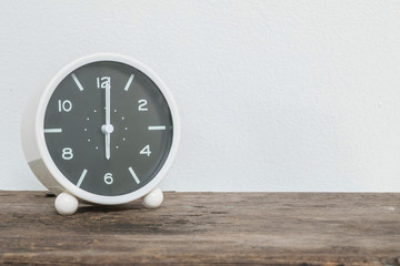 Closeup black and white alarm clock for decorate in 6 o'clock on old wood desk and white cement...