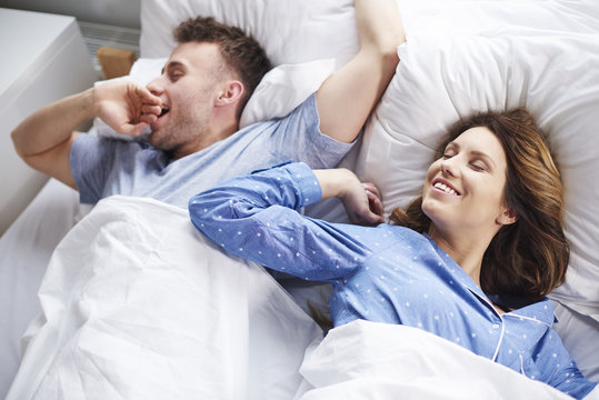 Couple stretching and yawning in bed