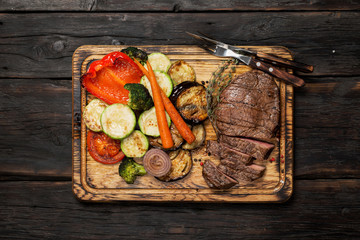 Grilled beef on the wooden board with a fork and a knife