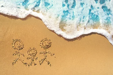 Familiensymbol - Mutter, Vater, Kind zeichnen auf dem Sand an einem goldenen, sonnigen Sandstrand im Ferienort in der Sommerferienruhe. Hintergrund mit sanften Wellen mit schaumblauem Meer. © Laura Pashkevich