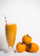 Persimmon smoothie with carrot and orange on wooden background