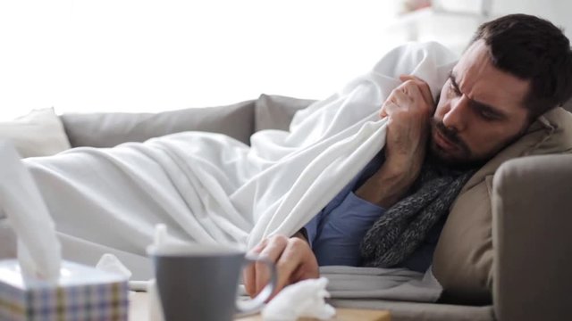 ill man with thermometer having flu at home