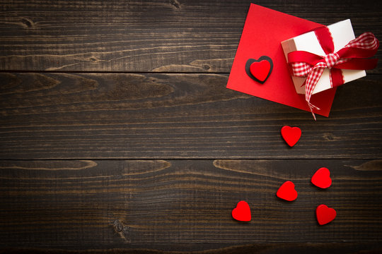 Valentine's Day background. Gift box, red hearts and Valentine's day card with copy space on the wooden desk