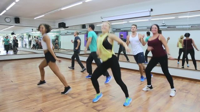 Young happy people studying zumba elements in dancing hall