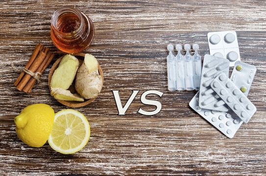 Ginger, lemon, honey and  different drugs on wooden background.Alternative remedies and traditional pills to treat colds and flu. Natural medicine vs conventional medicine concept.