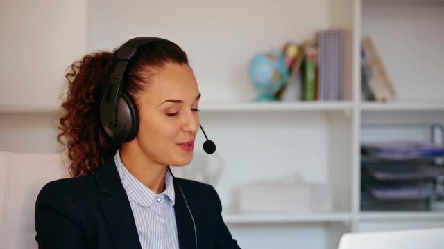 Portrait of young woman with headset working in call center