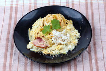 Spaghetti carbonara with crab, black dish.