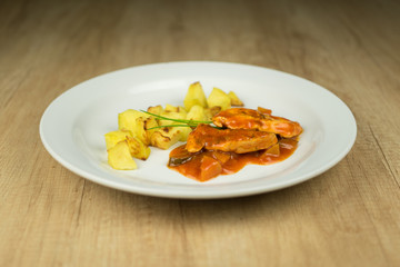 Meat with boiled potatoes on plate on wooden table