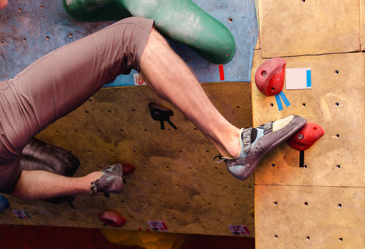 Foot in climbing shoes of a man on artificial boulder hook in gym