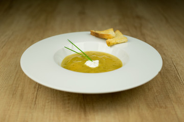Cream soup with toast on plate on wooden table