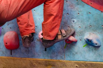 Foot in climbing shoes of a man on artificial boulder hook in gym
