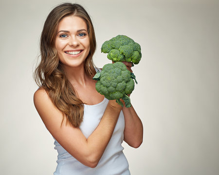 sporty smiling woman holding green vegetable.