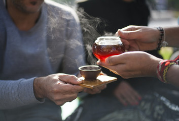 Chinese tea ceremony - hands holding clay cup and glass tea pot