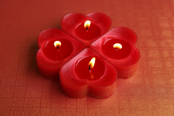 Heart shape candles. Four red candles burning.