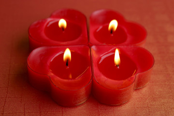 Fototapeta na wymiar Heart shape candles. Four red candles burning.