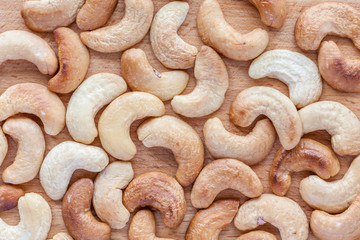 Texture of roasted organic cashew nuts on wooden board backgroun