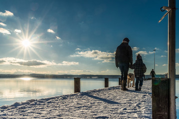 Mutter mit Kind auf langem Holzsteg am Starnberger See im Winter