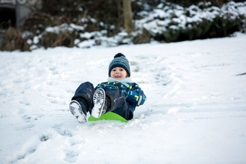 Fototapeta na wymiar Cute child, boy, sliding with bob in the snow, wintertime