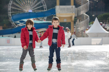 Happy children, boys, brothers with red jackets, skating during