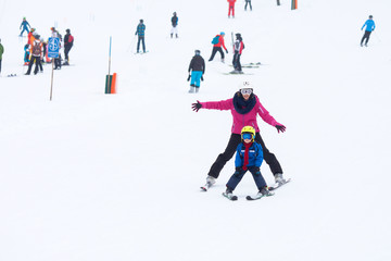 Sweet young boy and his mother, learning to ski on a mild ski sl